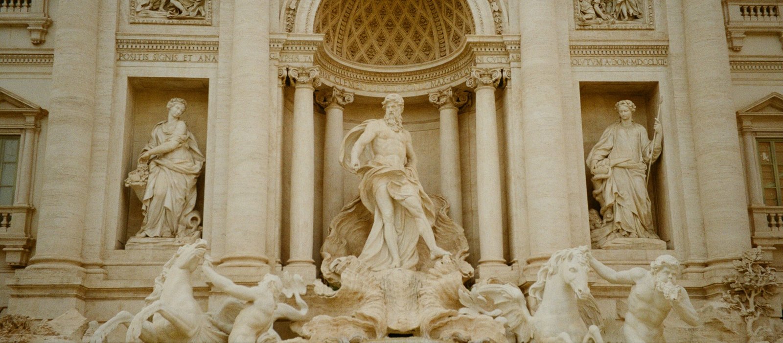 A fountain in front of a building with statues on it