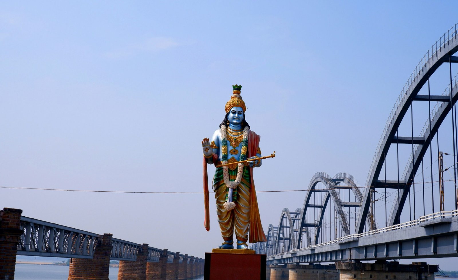 a statue of a hindu god stands in front of a bridge